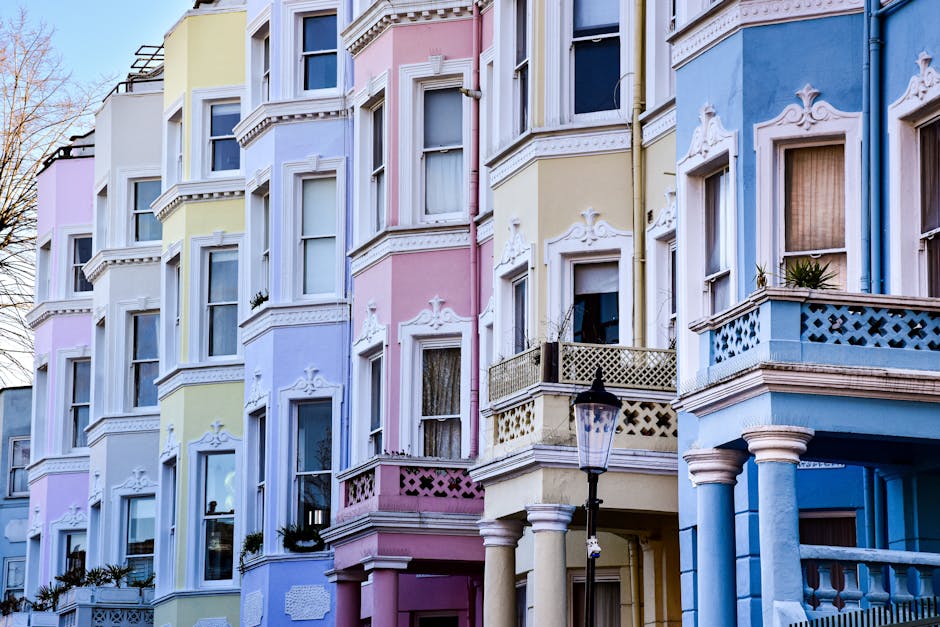 Close-up of a white residential building exterior on Portobello Road W11 in Notting Hill, featuring a decorative balustrade with white painted banisters and a partition wall. The smooth, painted surfa